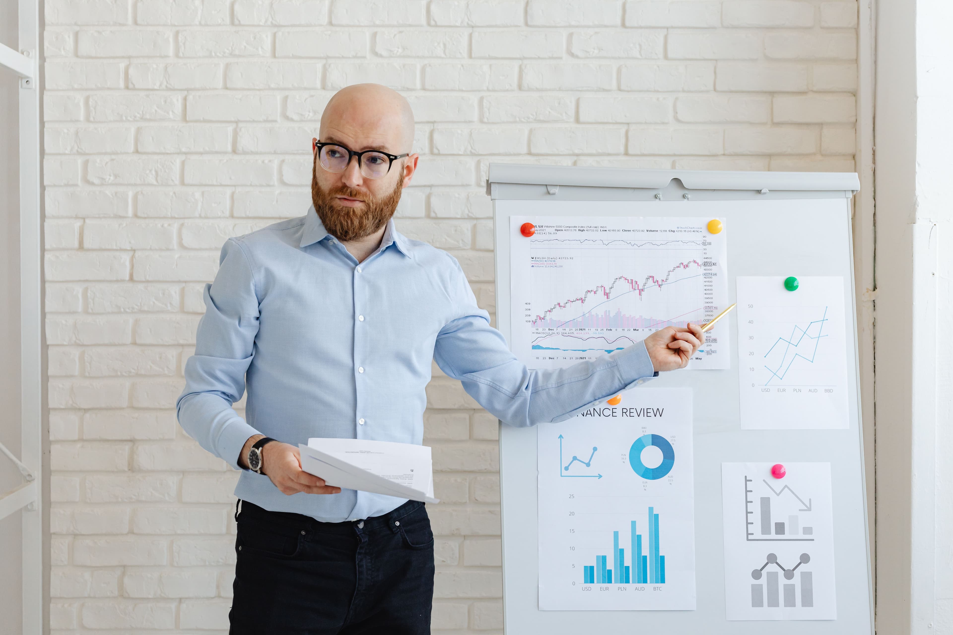 A presenter reviewing business charts on a whiteboard
