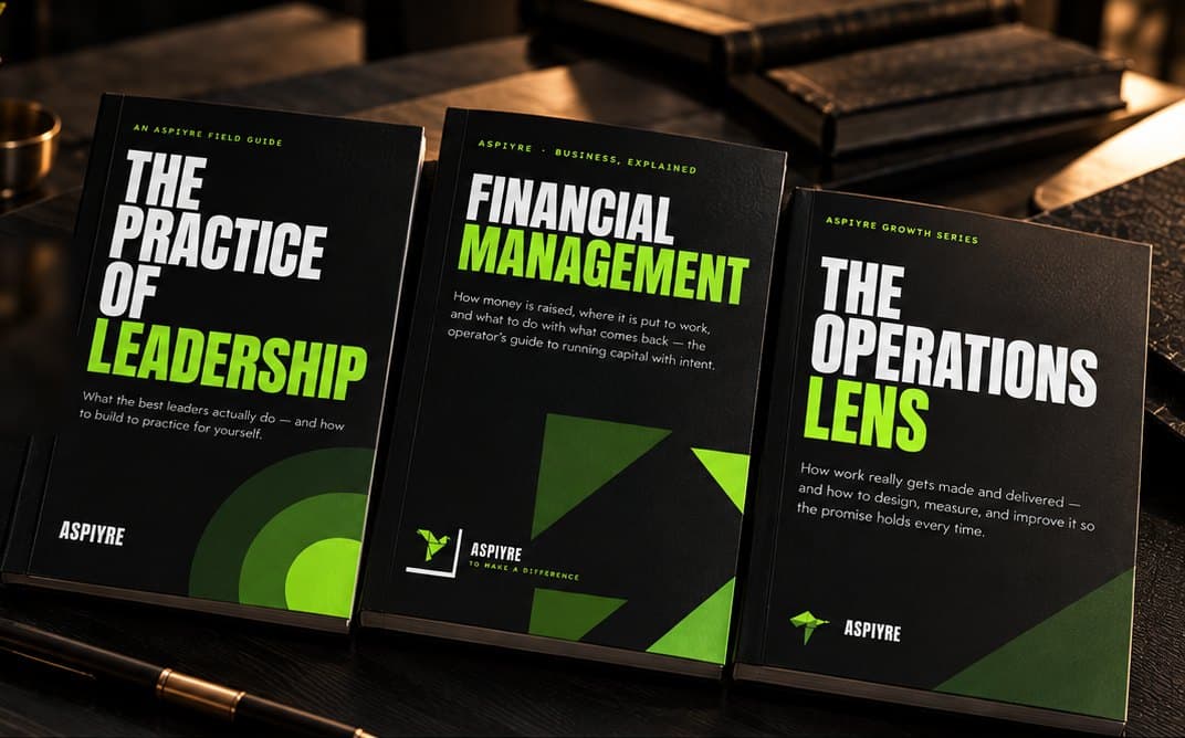 The Practice of Leadership, Financial Management and The Operations Lens guides standing on a dark desk.